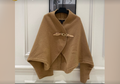 Camel wool cape poncho with leather buckle closure displayed on a hanger