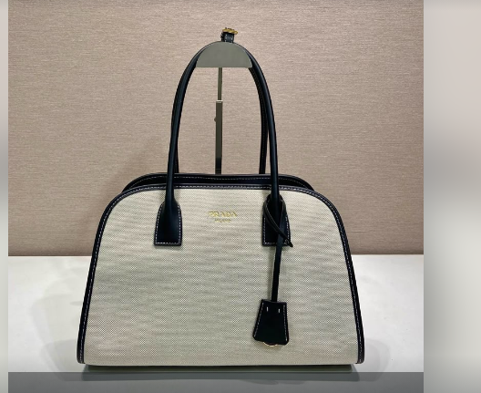 Cream canvas structured tote bag with black leather trim and gold hardware