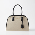Cream canvas tote bag with black leather trim, studio shot on white background
